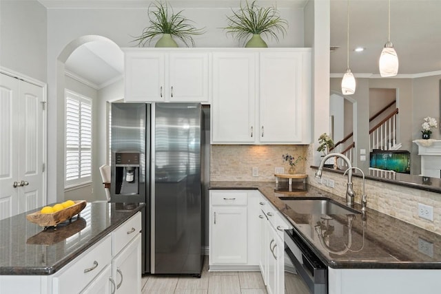 kitchen featuring appliances with stainless steel finishes, dark stone counters, sink, decorative light fixtures, and white cabinetry