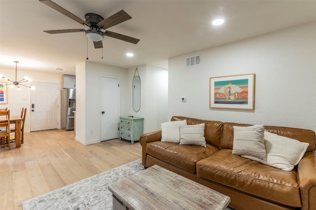 living room featuring light hardwood / wood-style floors and ceiling fan with notable chandelier