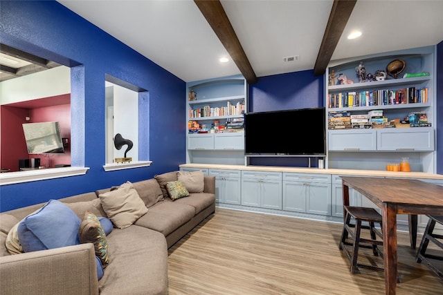 living room featuring light hardwood / wood-style floors, beam ceiling, and built in shelves