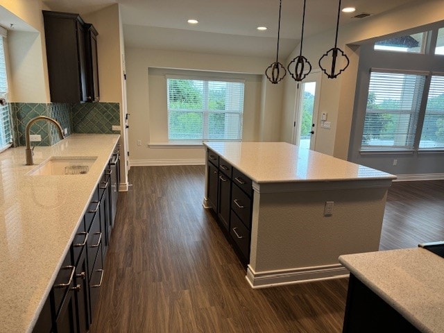 kitchen with a center island, backsplash, dark hardwood / wood-style flooring, hanging light fixtures, and sink