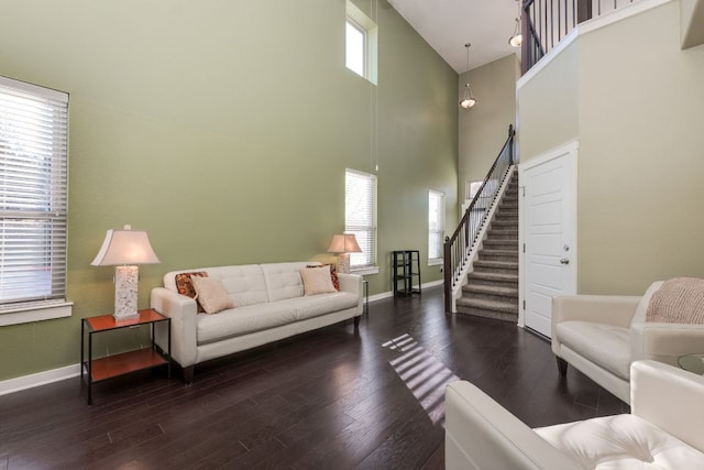 living area featuring stairway, a towering ceiling, baseboards, and wood finished floors