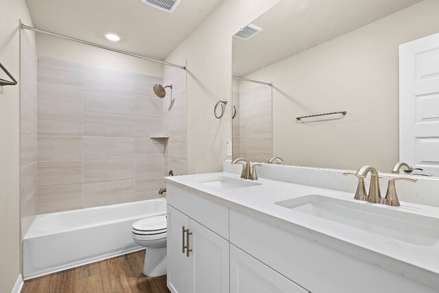 full bathroom with toilet, vanity, tiled shower / bath combo, and wood-type flooring