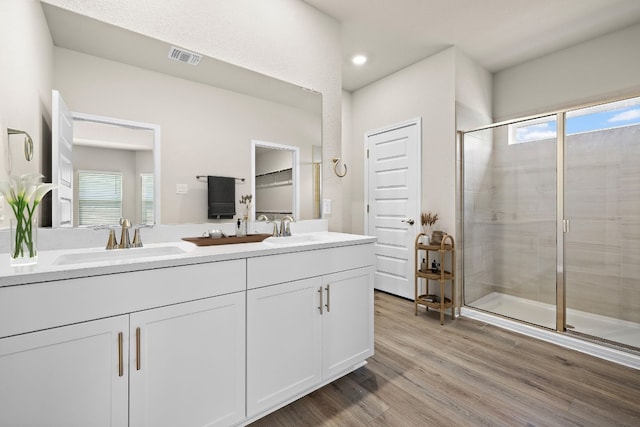 bathroom with a wealth of natural light, hardwood / wood-style flooring, vanity, and walk in shower