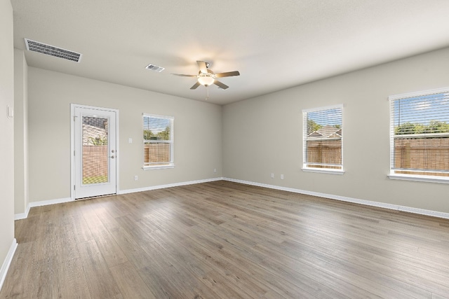 spare room with hardwood / wood-style floors, a wealth of natural light, and ceiling fan