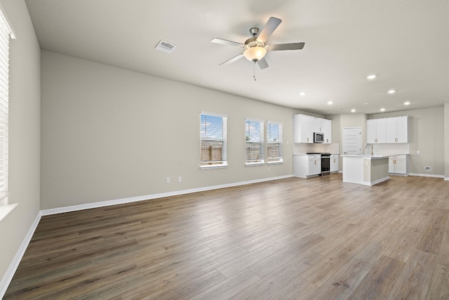 unfurnished living room with ceiling fan, sink, and light hardwood / wood-style floors