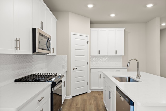 kitchen featuring light wood-type flooring, stainless steel appliances, decorative backsplash, and white cabinetry