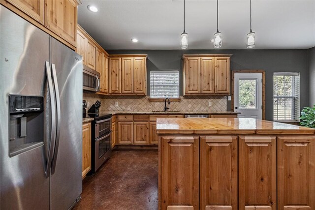 kitchen featuring tasteful backsplash, appliances with stainless steel finishes, a kitchen island, and pendant lighting