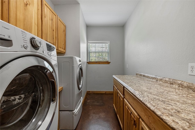 laundry room with washing machine and clothes dryer and cabinets