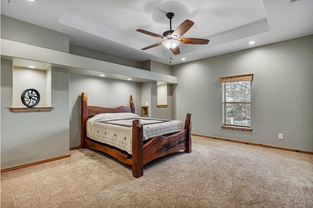 carpeted bedroom featuring a raised ceiling and ceiling fan