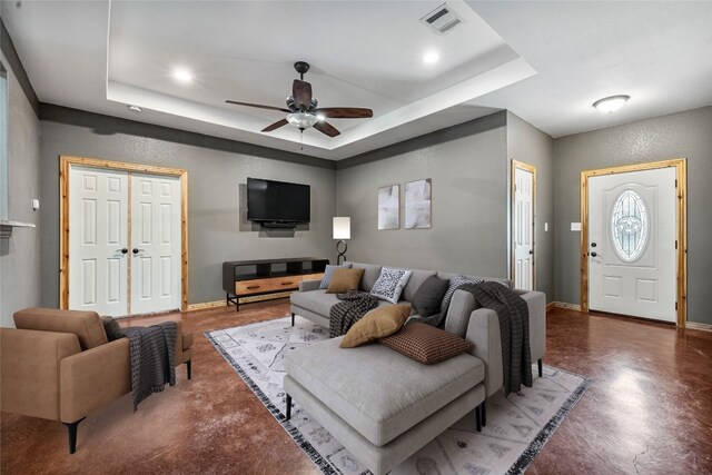 living room featuring ceiling fan and a raised ceiling