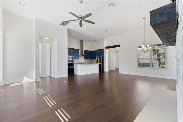 unfurnished living room featuring hardwood / wood-style flooring, a towering ceiling, and ceiling fan with notable chandelier