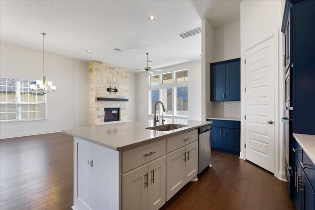 kitchen with sink, a fireplace, stainless steel dishwasher, decorative backsplash, and dark wood-type flooring