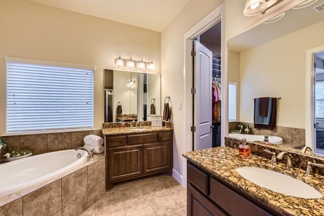 bathroom featuring vanity, tile patterned floors, and tiled tub