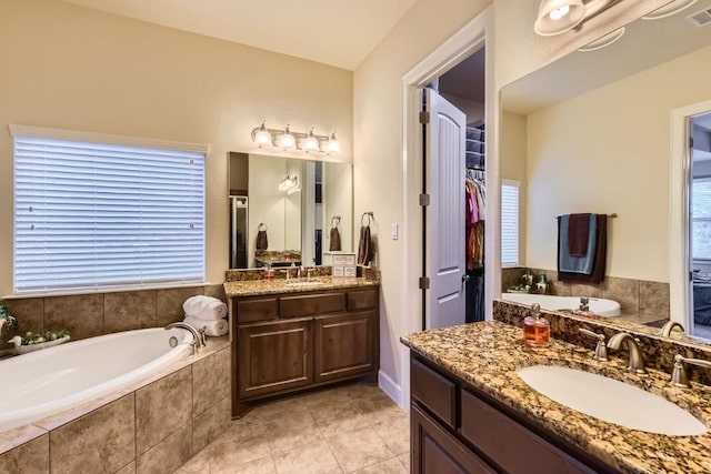 full bath featuring visible vents, tile patterned floors, a sink, a walk in closet, and two vanities