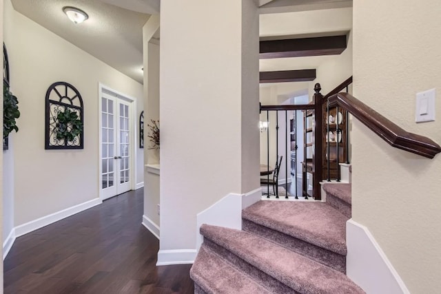 staircase featuring baseboards, beamed ceiling, wood finished floors, a textured ceiling, and french doors