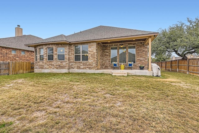 back of property with a fenced backyard, a lawn, and brick siding