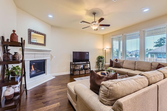 living room featuring ceiling fan, a tiled fireplace, and dark hardwood / wood-style flooring