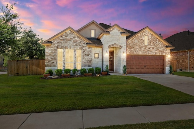 french provincial home featuring a garage, driveway, a front lawn, and brick siding