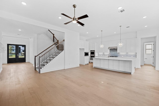 unfurnished living room featuring sink, ceiling fan, french doors, and light hardwood / wood-style floors