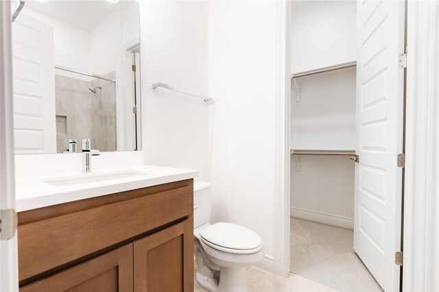 bathroom with tiled shower, toilet, and vanity