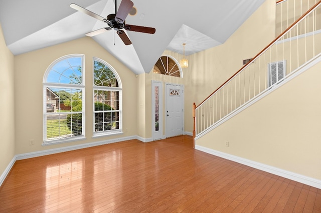 foyer entrance with hardwood / wood-style floors, ceiling fan with notable chandelier, and vaulted ceiling