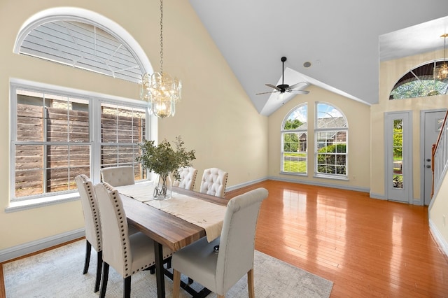 dining room featuring ceiling fan with notable chandelier, high vaulted ceiling, and light hardwood / wood-style flooring