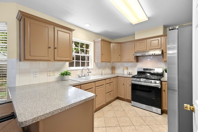 kitchen featuring sink, tasteful backsplash, kitchen peninsula, light tile patterned floors, and appliances with stainless steel finishes