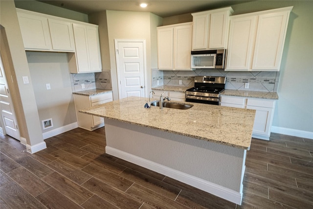 kitchen featuring appliances with stainless steel finishes, white cabinetry, a kitchen island with sink, and sink