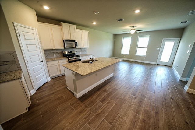 kitchen featuring white cabinets, sink, stainless steel appliances, and an island with sink