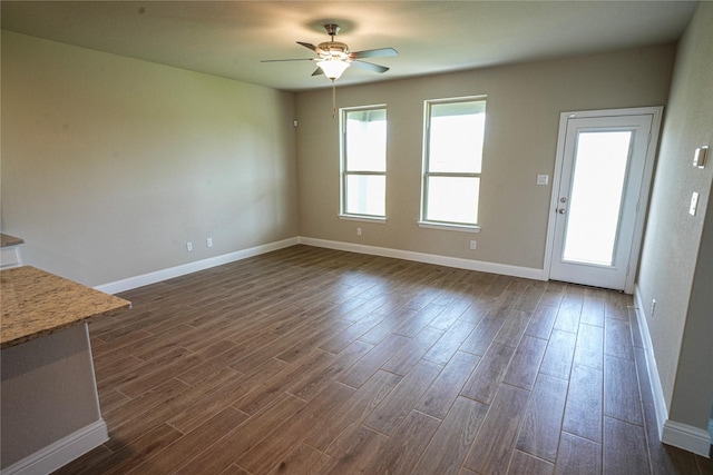 unfurnished living room featuring ceiling fan and dark wood-type flooring