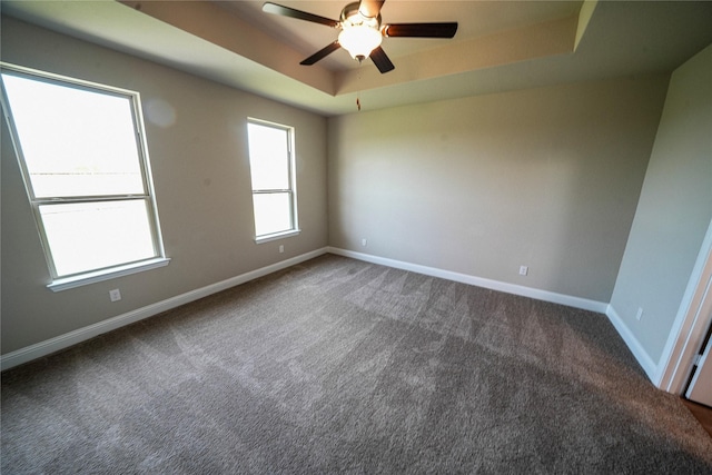 carpeted empty room featuring ceiling fan and a raised ceiling