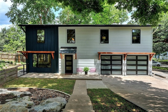 view of front of property with a garage, concrete driveway, board and batten siding, and fence