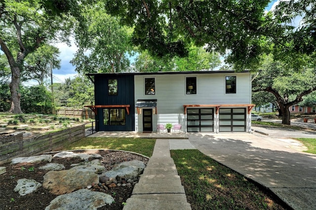 view of front of home with concrete driveway, an attached garage, and fence