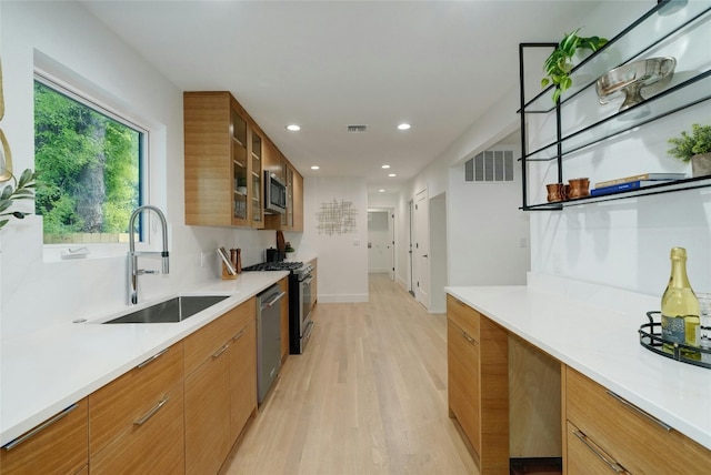 kitchen featuring visible vents, appliances with stainless steel finishes, glass insert cabinets, light countertops, and a sink