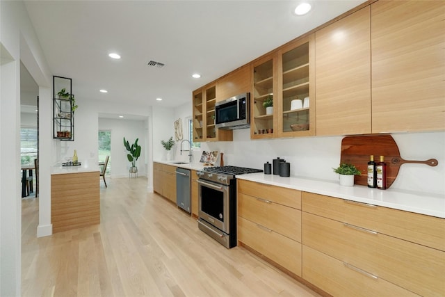 3104 Santa Monica Dr, Austin, TX 78741 - kitchen featuring appliances with stainless steel finishes, a sink, modern cabinets, recessed lighting, and light wood-style flooring