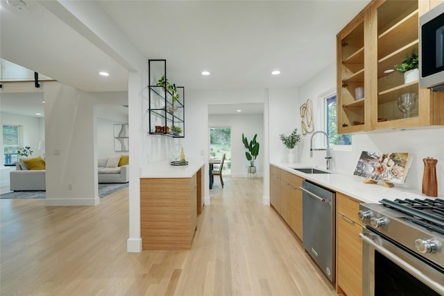 kitchen featuring recessed lighting, stainless steel appliances, a sink, light wood-style floors, and light countertops