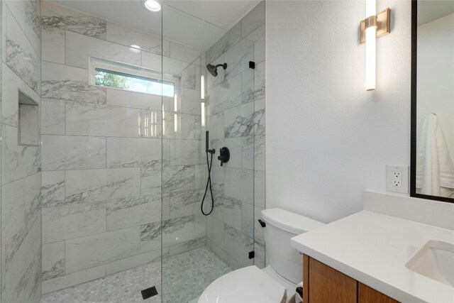 bathroom featuring a tile shower, vanity, and toilet