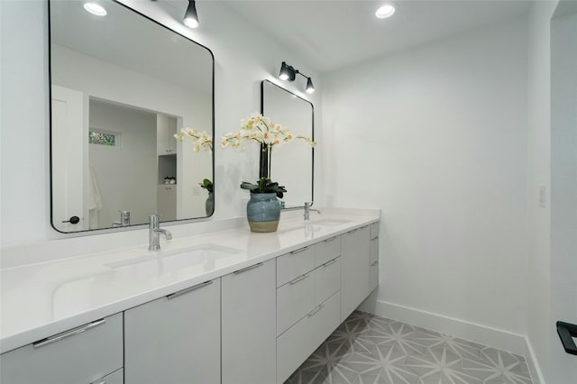 bathroom with recessed lighting, a sink, baseboards, and double vanity