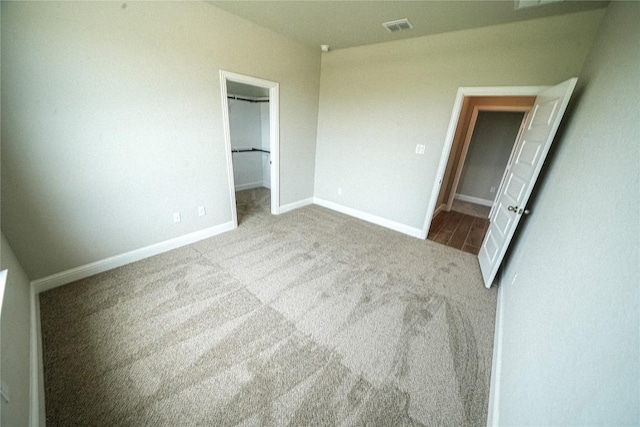 unfurnished bedroom with baseboards, a spacious closet, visible vents, and carpet flooring