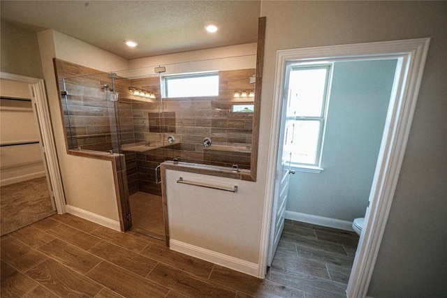 bathroom with wood finish floors, a shower stall, toilet, and recessed lighting