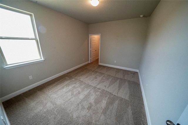 carpeted spare room featuring baseboards