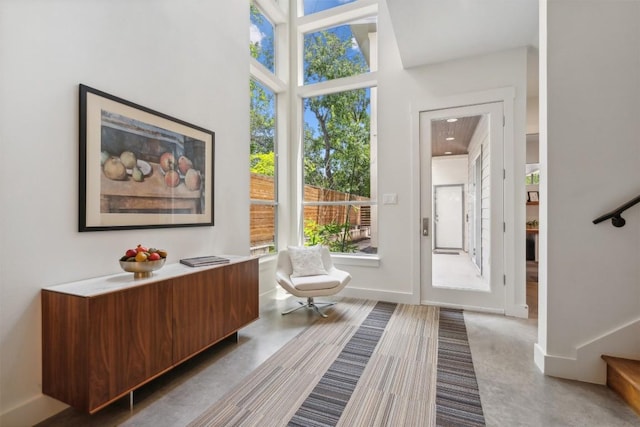 entryway with stairway, baseboards, and finished concrete floors