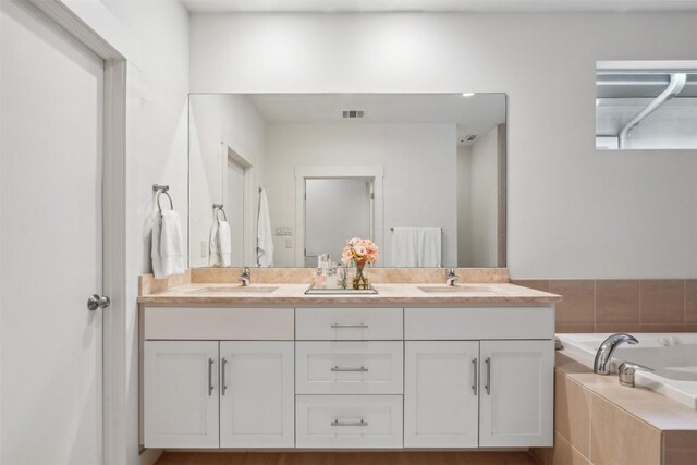 bathroom featuring vanity and a relaxing tiled tub