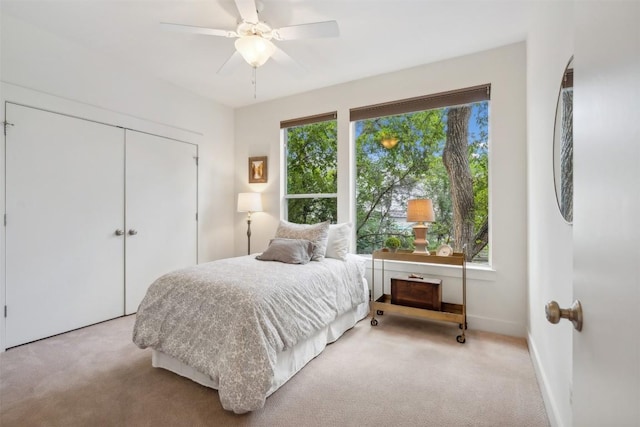 bedroom with baseboards, a closet, light carpet, and ceiling fan