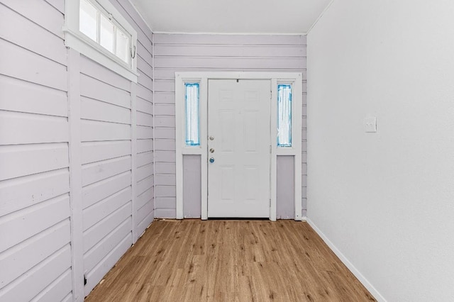 foyer entrance with wooden walls and light hardwood / wood-style flooring