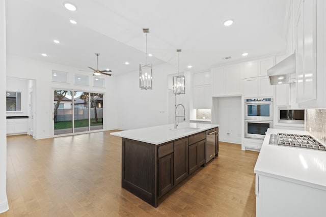 kitchen with light wood-type flooring, a center island with sink, stainless steel appliances, and sink