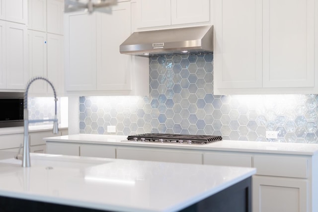 kitchen with tasteful backsplash, white cabinetry, stainless steel gas cooktop, and wall chimney exhaust hood