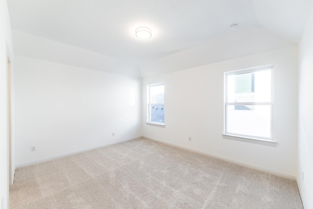 unfurnished room featuring light carpet and vaulted ceiling