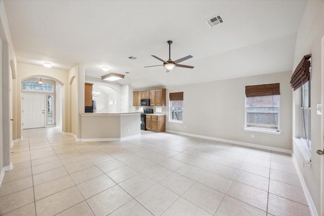 unfurnished living room with a wealth of natural light, light tile patterned floors, and ceiling fan