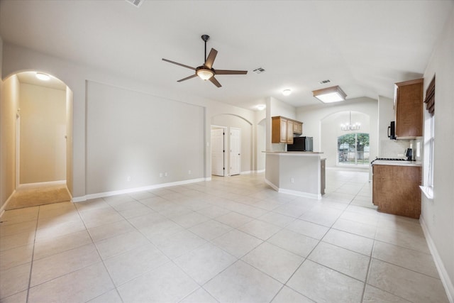 unfurnished living room featuring ceiling fan with notable chandelier, vaulted ceiling, and light tile patterned flooring